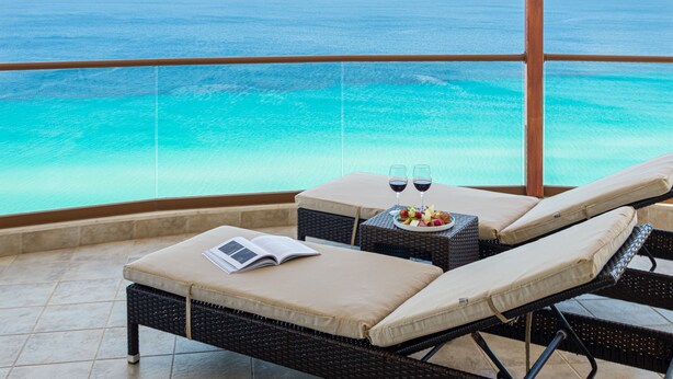 A balcony with two lounge chairs, a small table with a plate of fruit and two glasses of red wine, and a book. - Blue Bay Halkidiki “Adults Only ” (Kassandra)