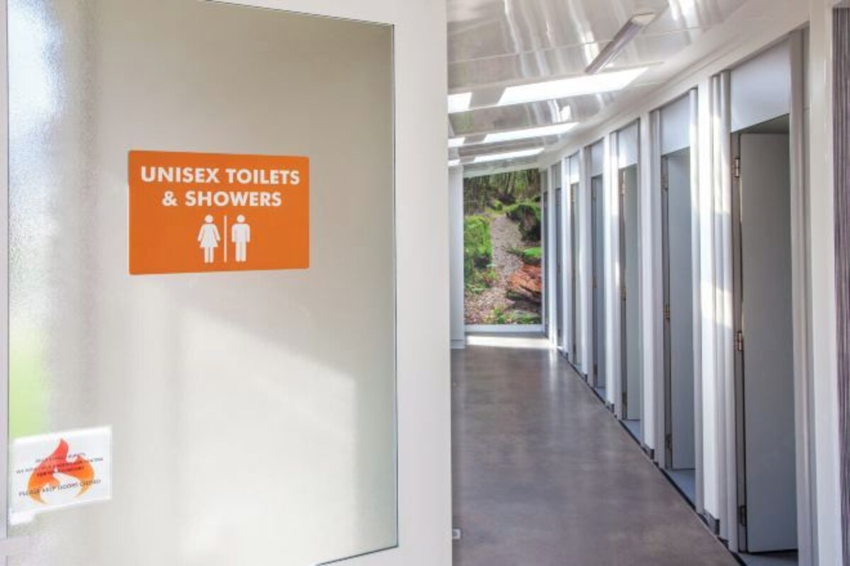 Pasillo con un cartel que indica baños y duchas unisex.