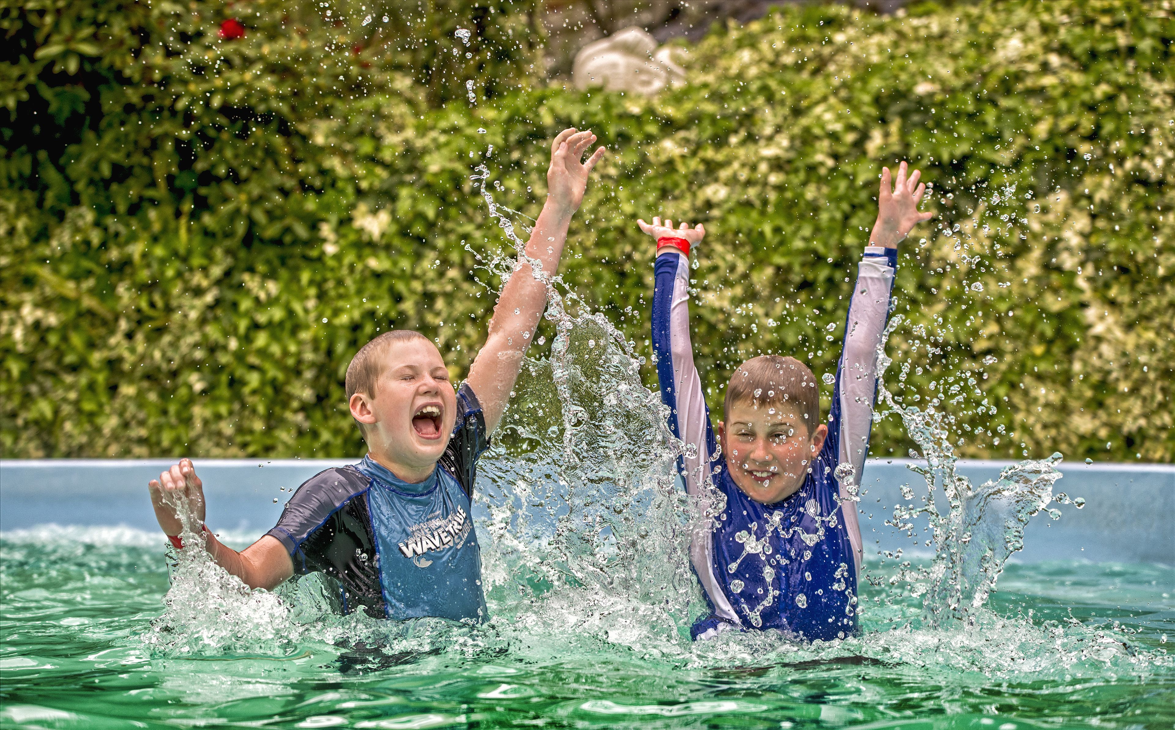 Dues persones banyant-se en una piscina amb aigua esquitxant.