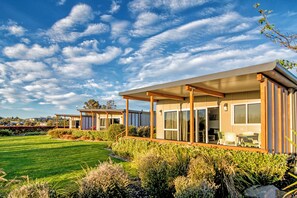 Une maison moderne dotée d’un patio couvert, d’une pelouse et d’un jardin.