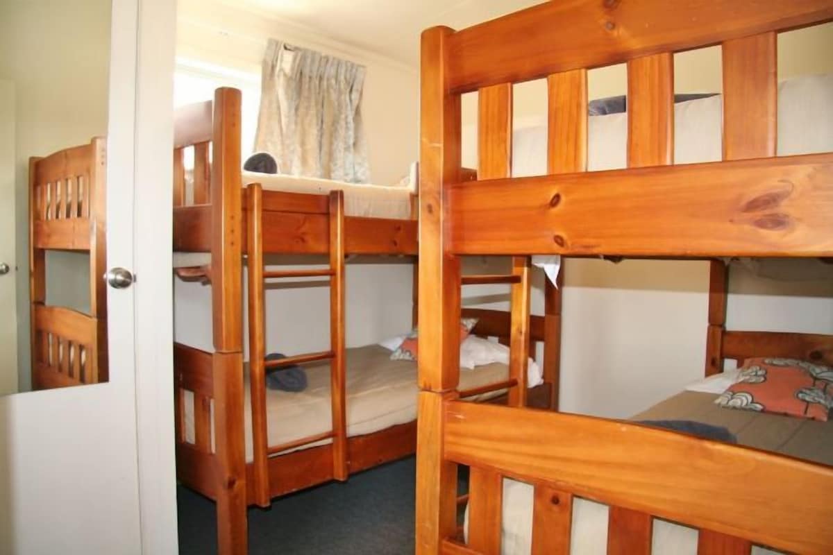 Habitación con literas, una puerta de madera y una ventana con cortinas.
