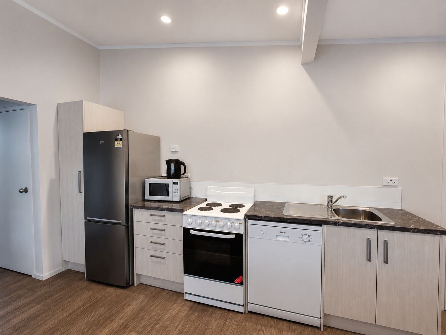 Eine kompakte Küche mit Kühlschrank, Mikrowelle, Herd, Backofen und Geschirrspüler.