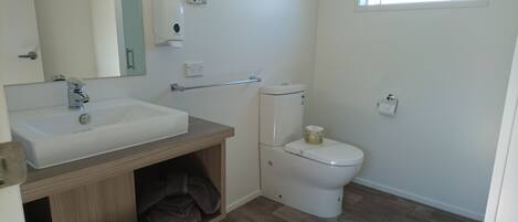 Un baño con un lavamanos blanco, un inodoro y un espejo.