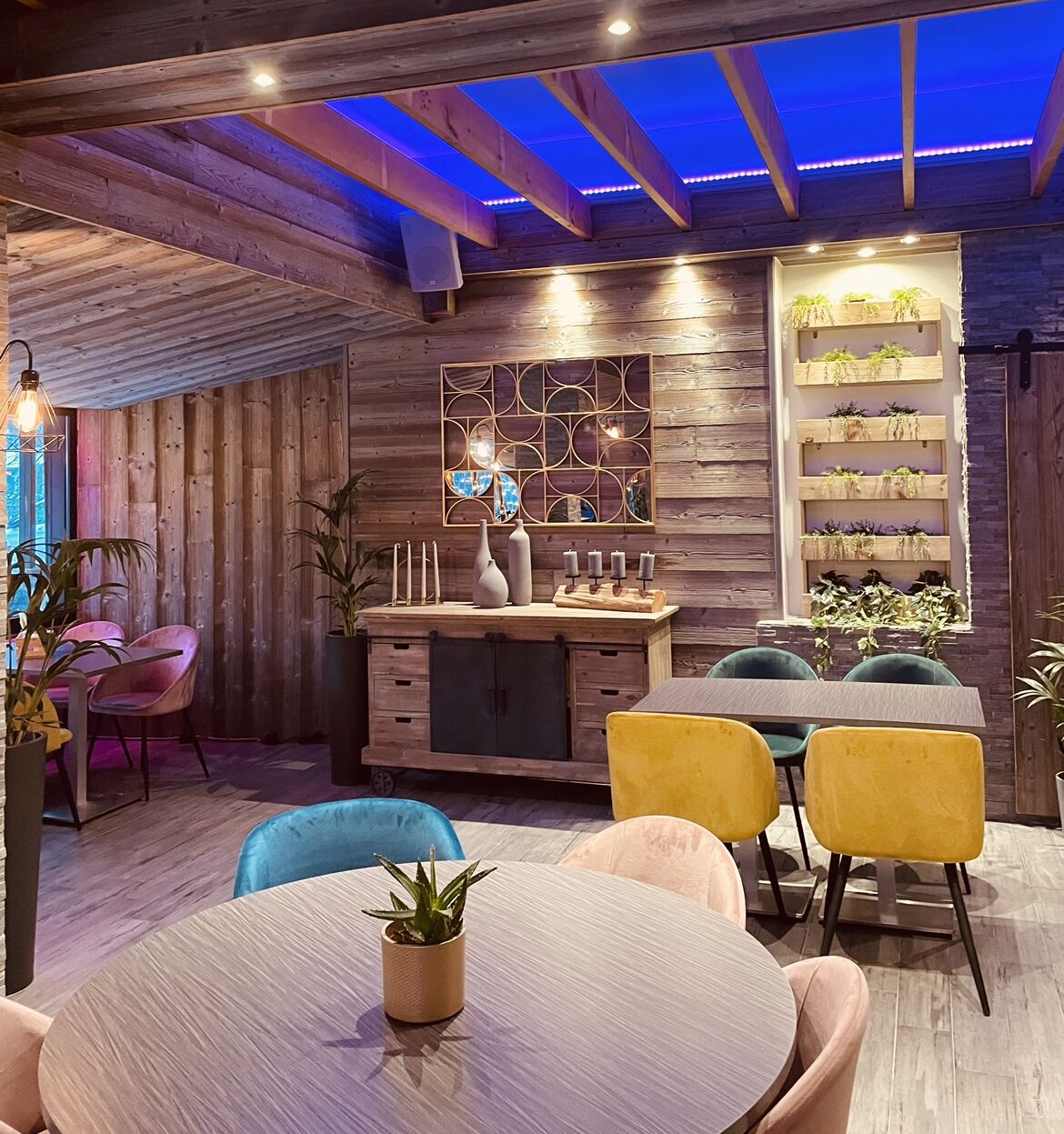 Un comedor acogedor con paredes de madera, una mesa central y sillas coloridas.