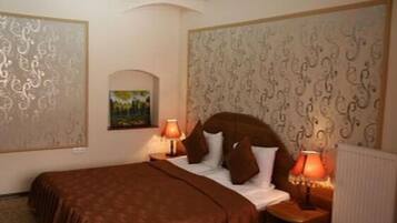 Una habitación de hotel con una cama grande, dos lámparas de noche, un radiador y un panel decorativo en la pared.
