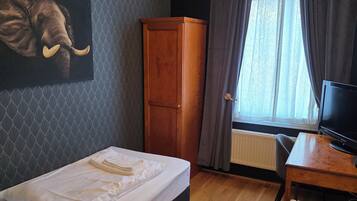 Une chambre d’hôtel comprenant un lit, un bureau, une télévision, une armoire et une œuvre d’art représentant un éléphant, accrochée au mur.