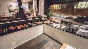 Ein reichhaltiges Buffet mit verschiedenen Speisen und einem Sitzbereich im Hintergrund.
