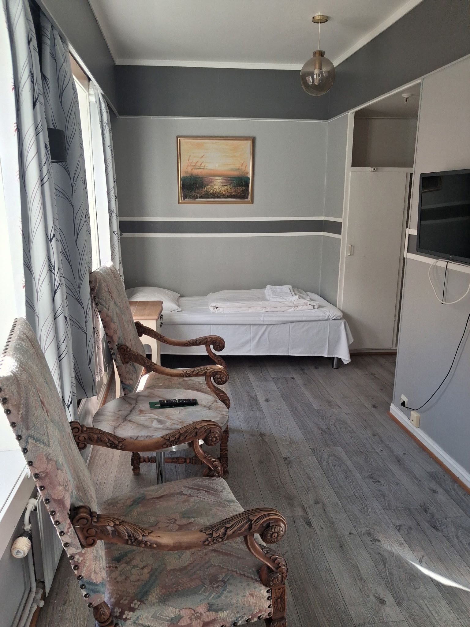 Un dormitorio con una cama, una silla, un cuadro y un armario.
