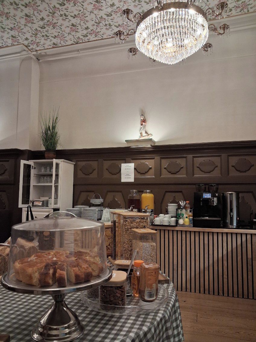 A buffet area with a glass-covered food display, a coffee station, and a decorative ceiling light.