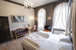 Una habitación de hotel con una cama grande, un escritorio, una silla, un televisor y un espejo.