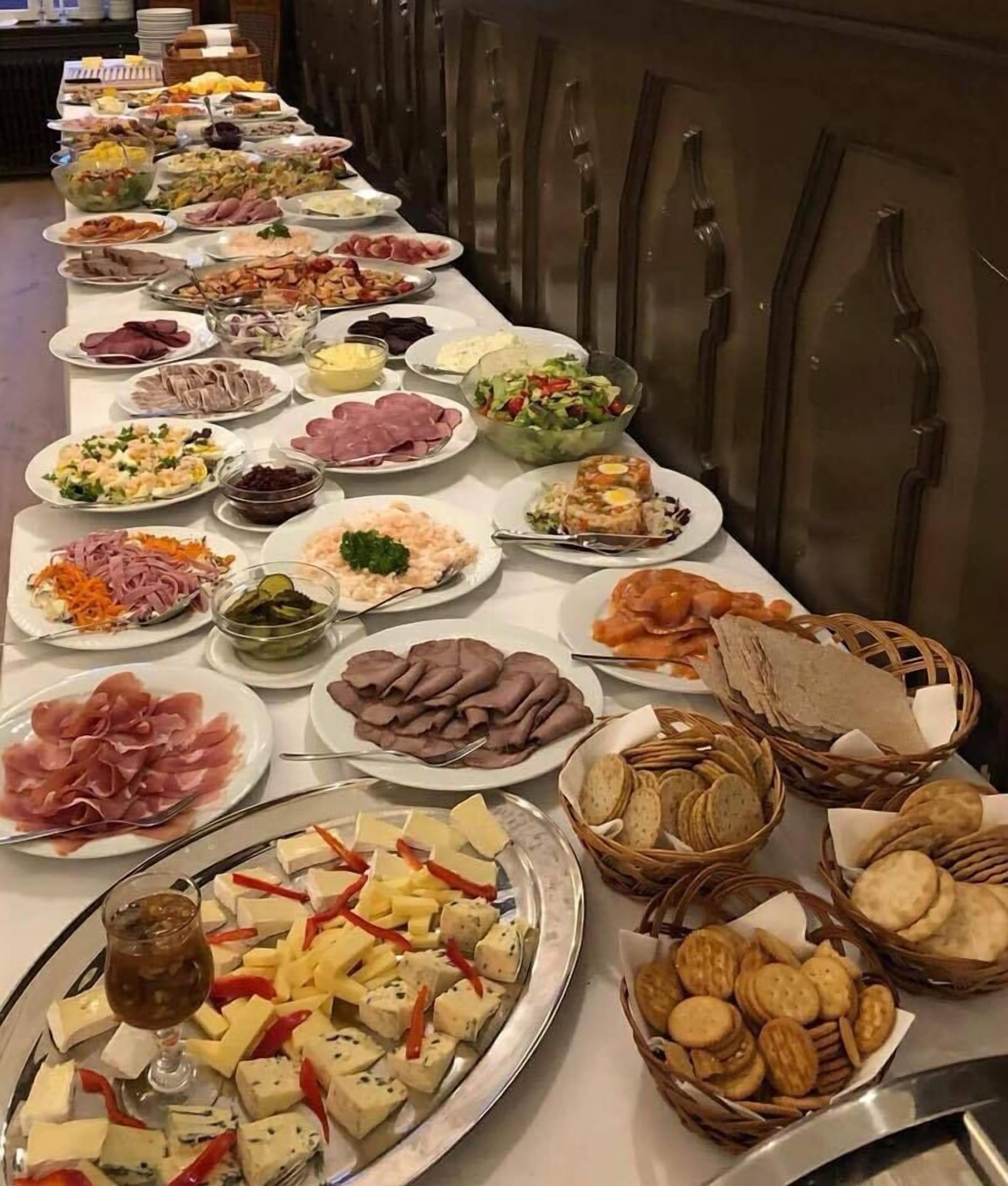 A buffet table with various food items including meats, cheeses, salads, and crackers.