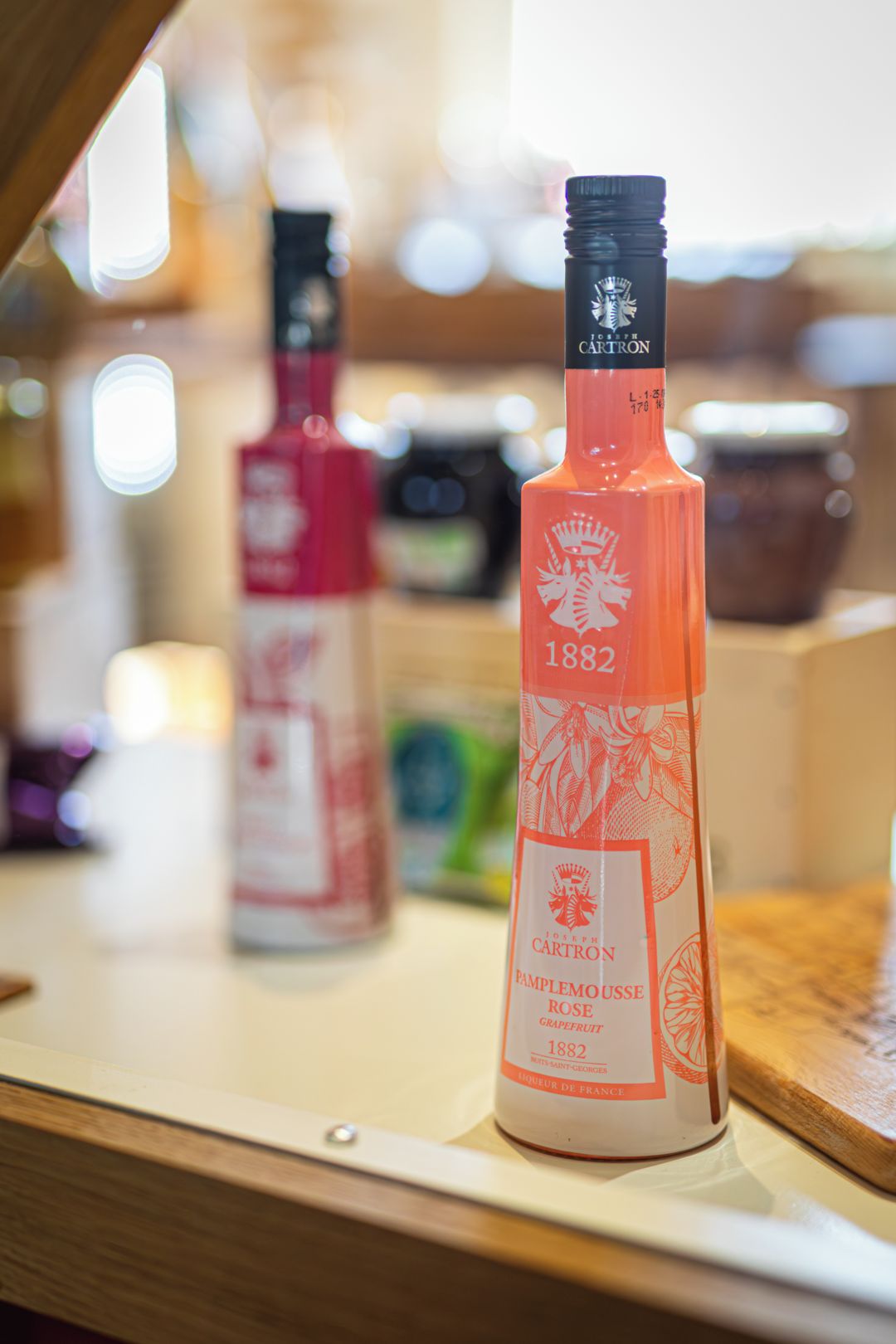 Dos botellas de Pamplemousse Rose Grapefruit 1882 sobre una superficie de madera.