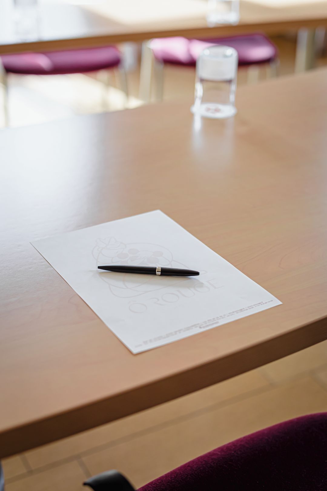 Une table en bois sur laquelle se trouvent une feuille de papier blanche et un stylo.