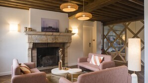 A cozy living room with a fireplace, comfortable seating, and pendant lighting.