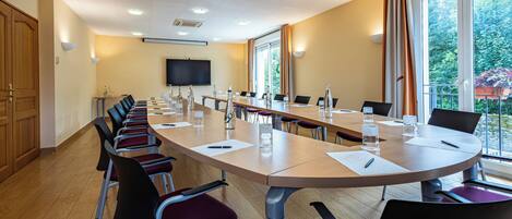 A conference room with a long table, chairs, and a television screen.