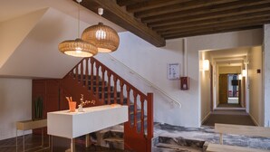 A staircase with wooden railings, a white console table, and wicker pendant lights.