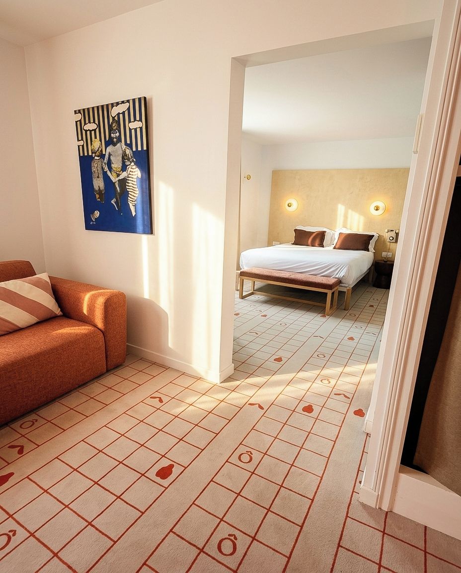 Una habitación de hotel con cama, un banco, un sofá y un cuadro en la pared.