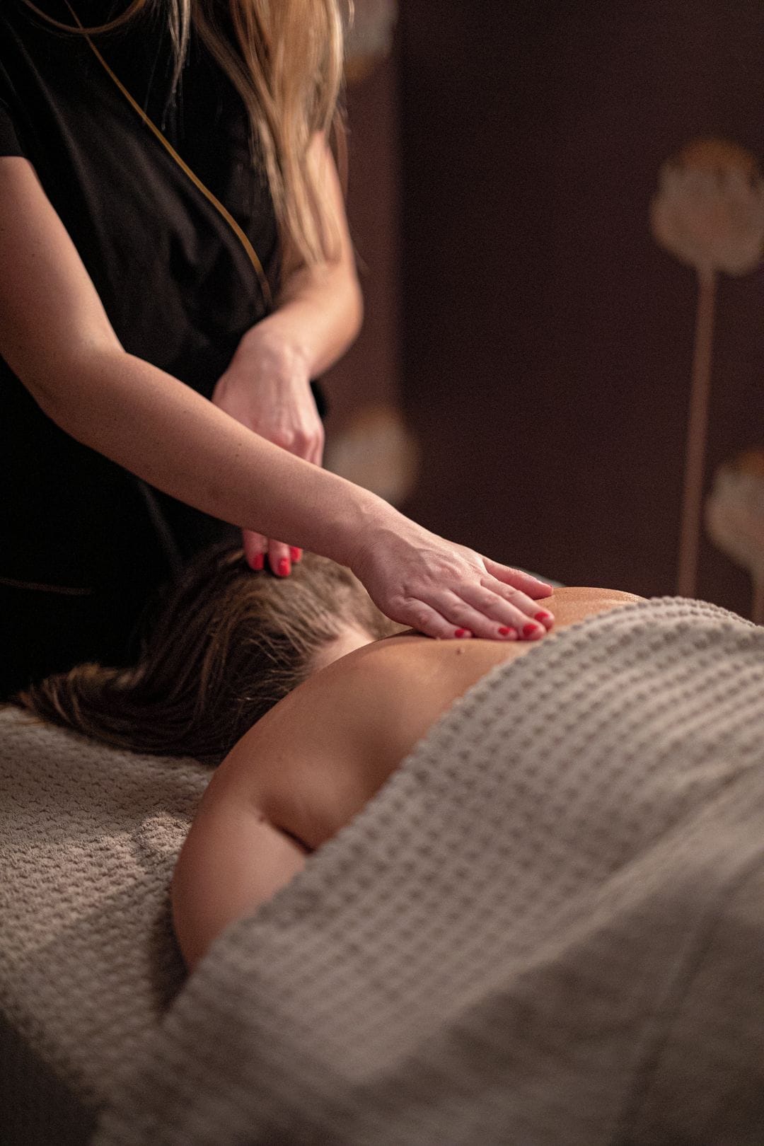 Sessão de massagem em andamento: uma pessoa de bruços em uma mesa de tratamento, recebendo massagem nas costas de outra pessoa.