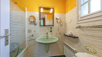 A bathroom with a green sink, a mirror, a towel rack, and a shower.