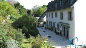 A traditional stone building with a steeply pitched roof, a small porch, and a gravel pathway leading to the entrance. - Hotel De la Corniche (Brest)