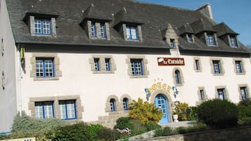 Experience the charm of Hotel de la Corniche, featuring a classic European design with a beautiful arched entrance and lush gardens.