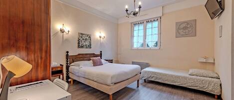 Un dormitorio con cama de madera, una mesita de noche, una lámpara, un radiador, una ventana y cuadros en la pared.