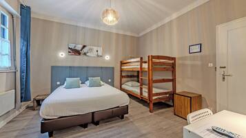 A bedroom with a large bed, a bunk bed, a desk, and a chair.