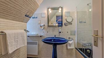 Un bagno con un lavandino blu, uno specchio e un portascopevoli.