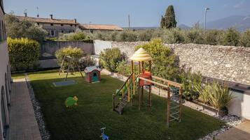 Children can play safely in this enclosed outdoor play area featuring a playhouse, slide, and climbing structure.