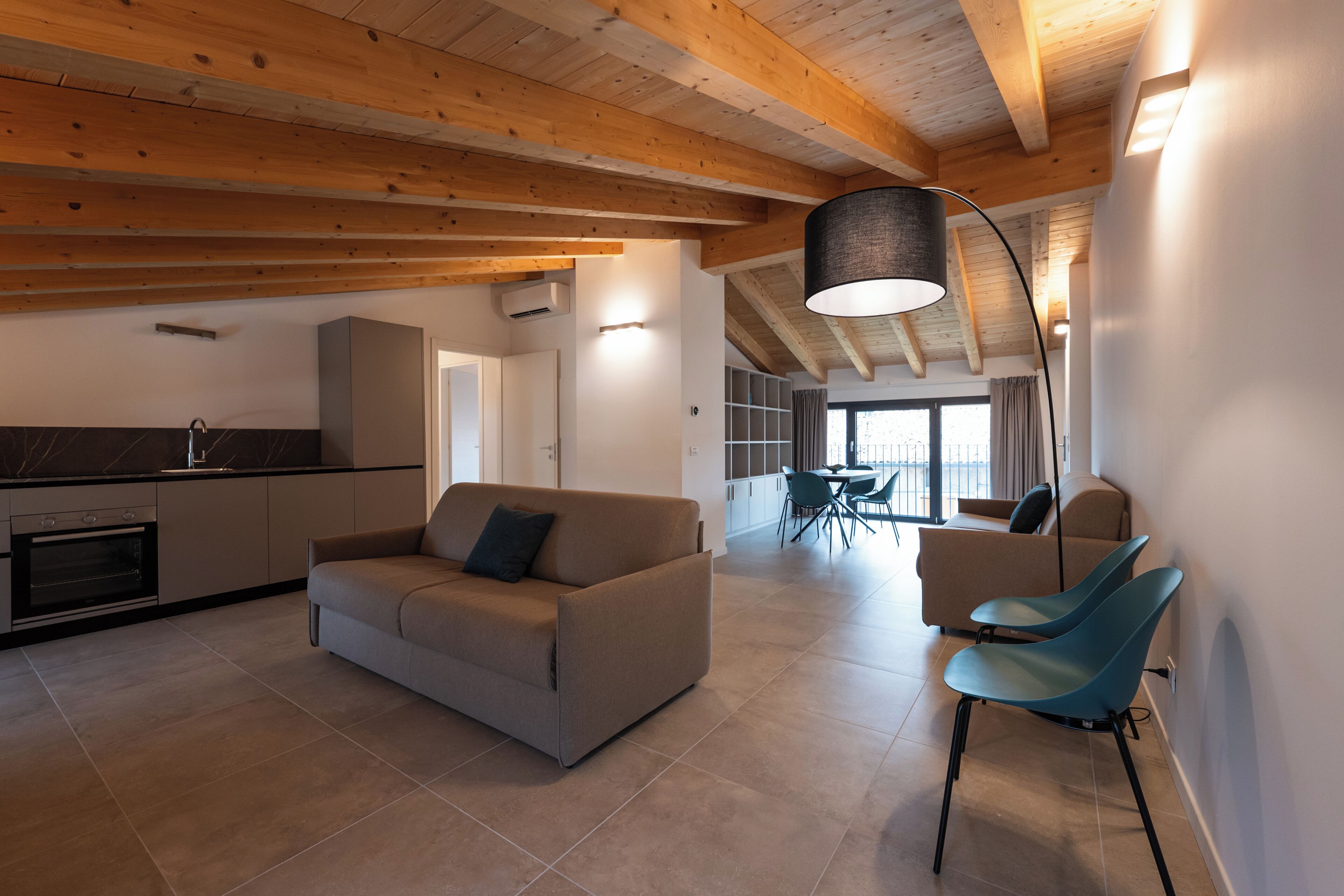 A modern interior with a kitchen, a dining area, and a living space with a sofa and chairs.