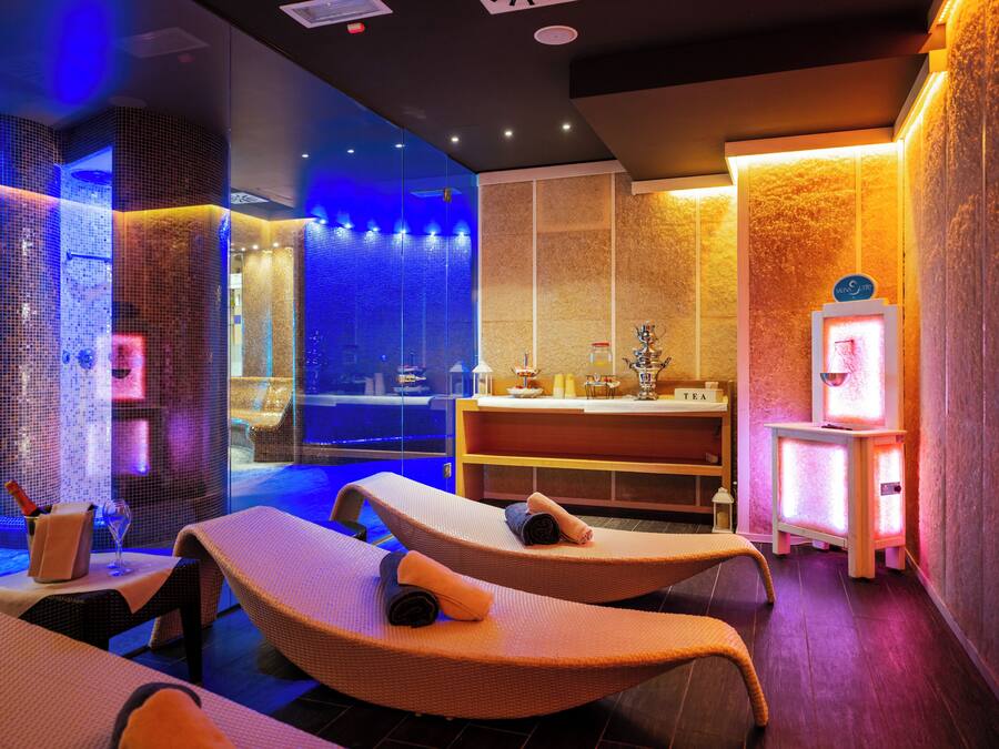 A spa room with two reclining chairs, a reception desk, and a wall with a textured pattern.