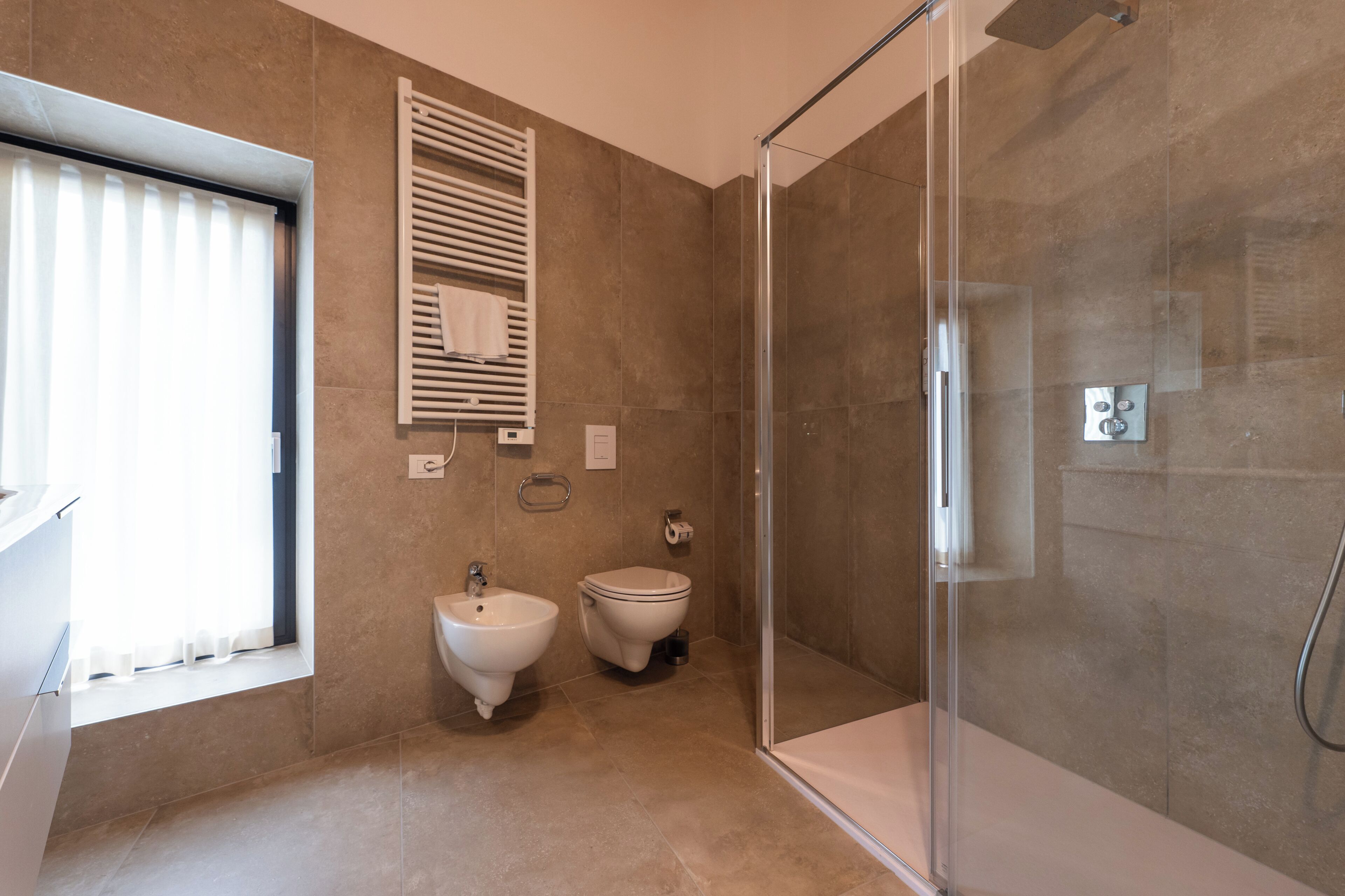 A modern bathroom with a glass shower enclosure, a bidet, and a toilet.