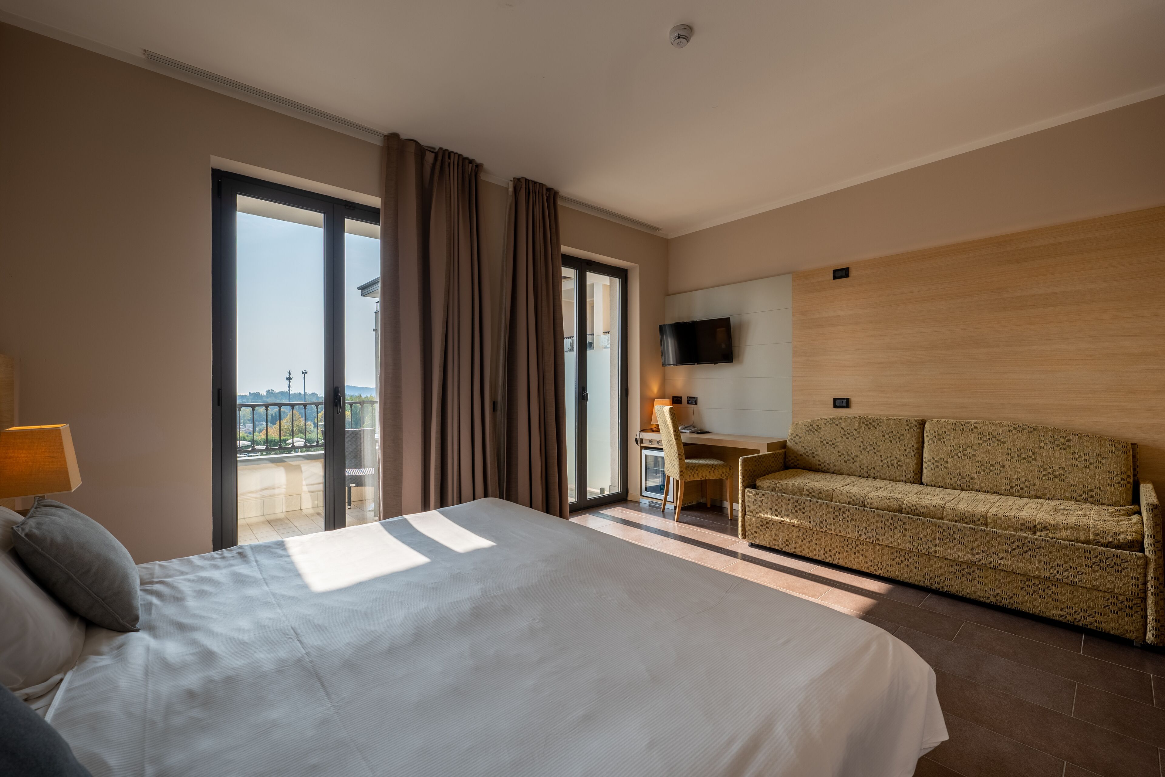 Una habitación de hotel con una cama grande, un sofá, un escritorio y un televisor.