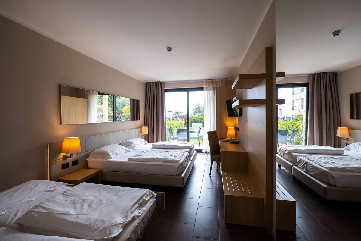 Habitación de hotel con dos camas, un escritorio, una silla y un televisor.