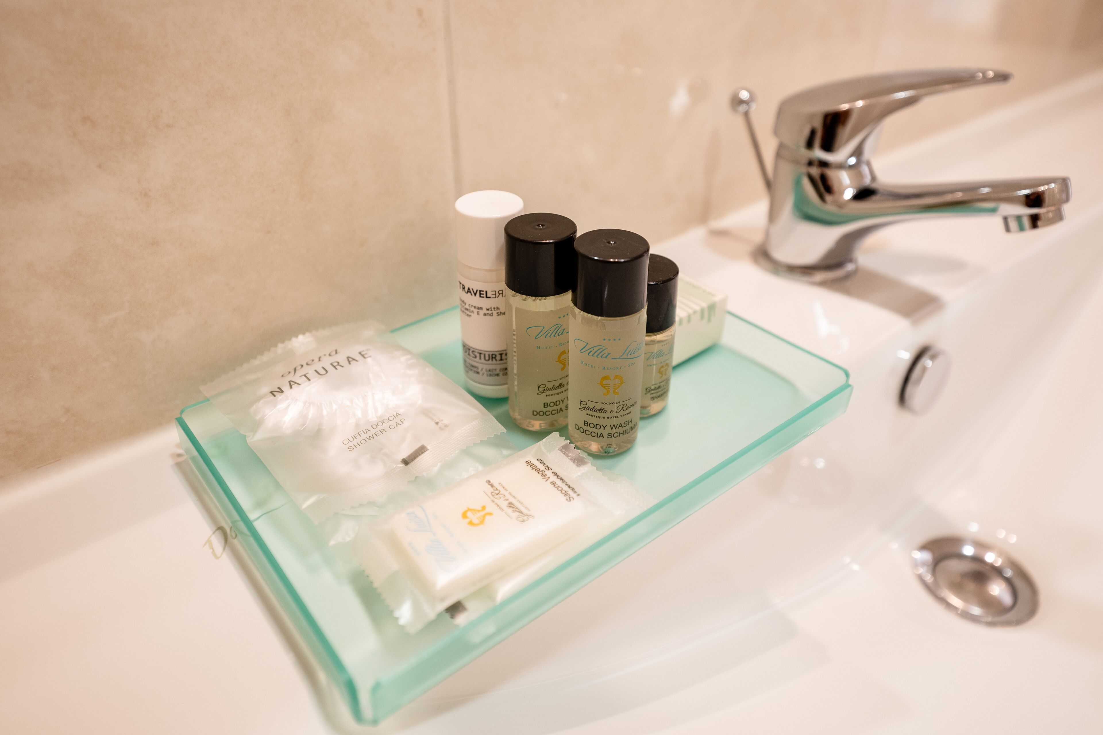 A bathroom with a glass shelf holding toiletries and a white sink with a chrome faucet.