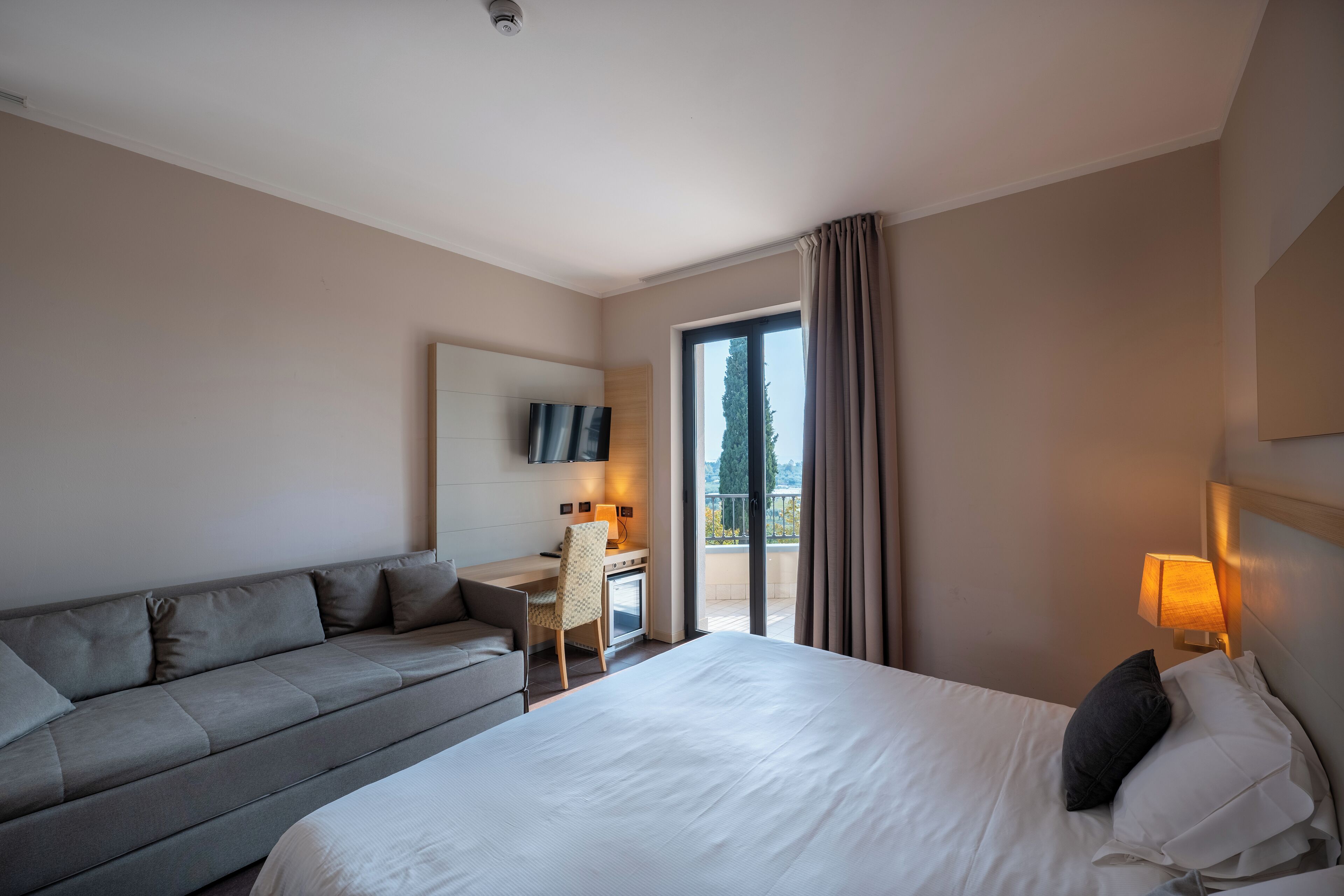 Een hotelkamer met een bed, een bank, een bureau en een televisie.
