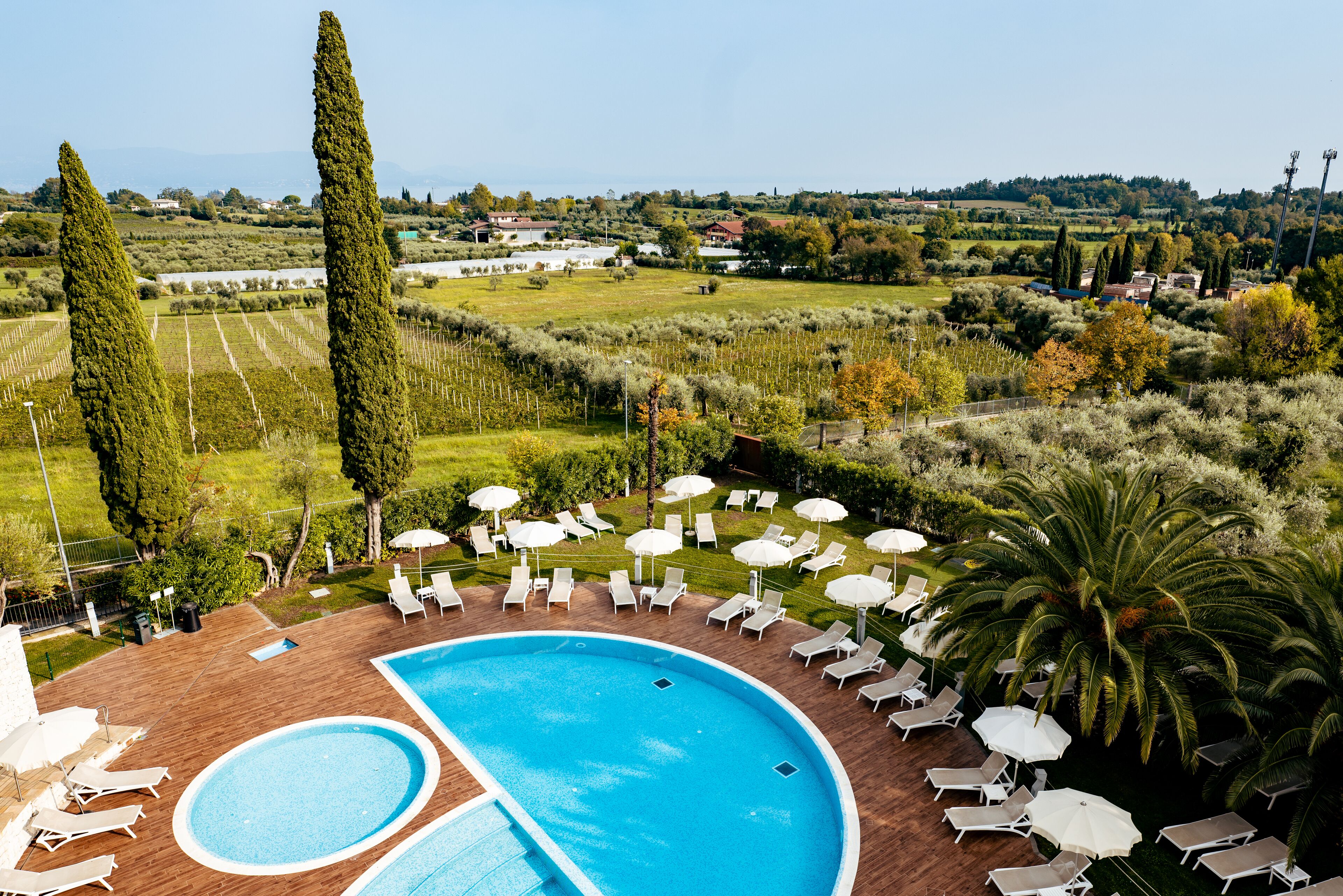 A pool area with two pools, lounge chairs, and umbrellas.