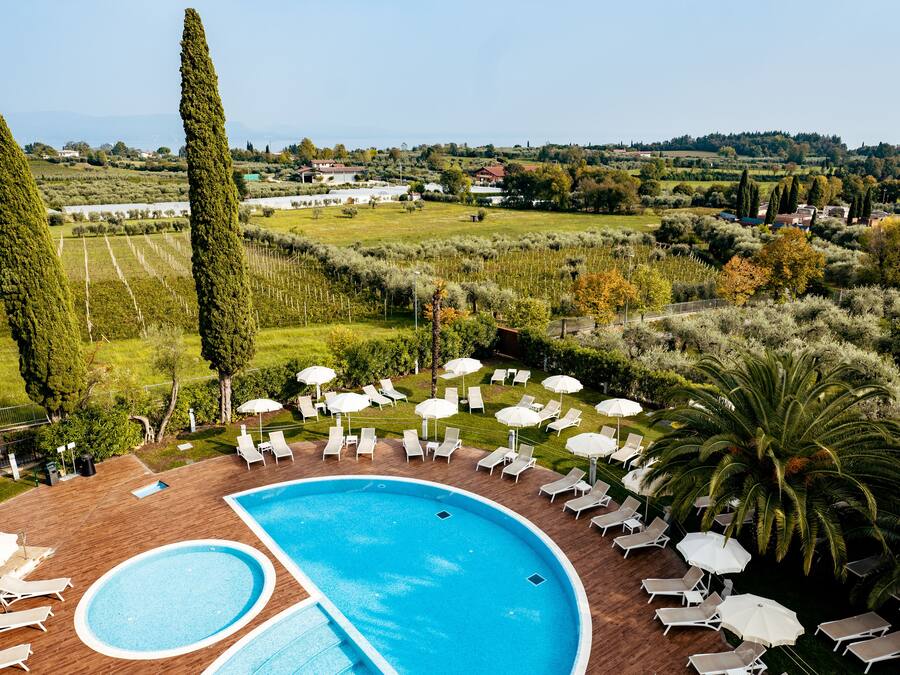 A pool area with two pools, lounge chairs, and umbrellas.