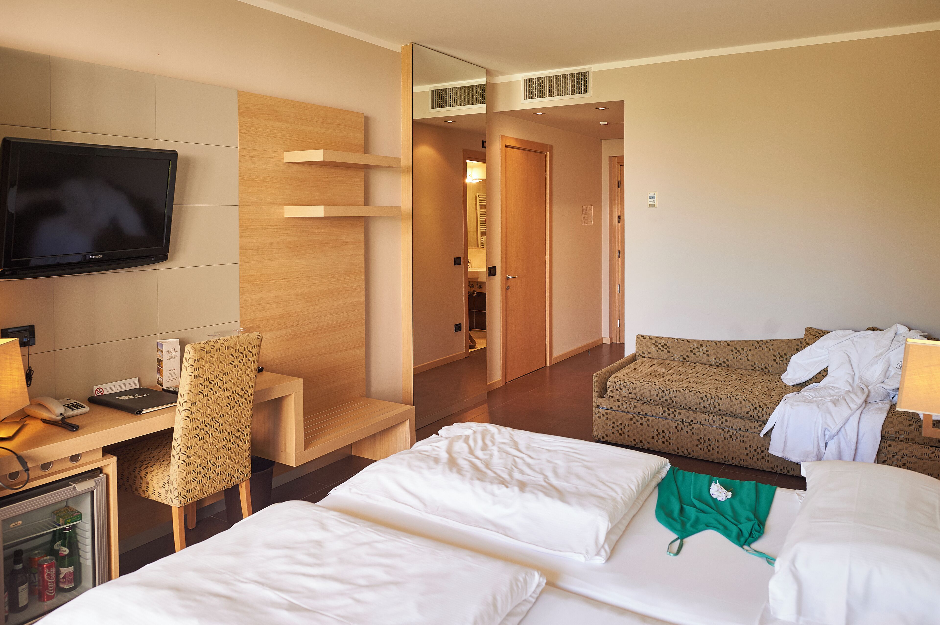 Une chambre d’hôtel comprenant un lit, un bureau avec une chaise, une télévision et une armoire.