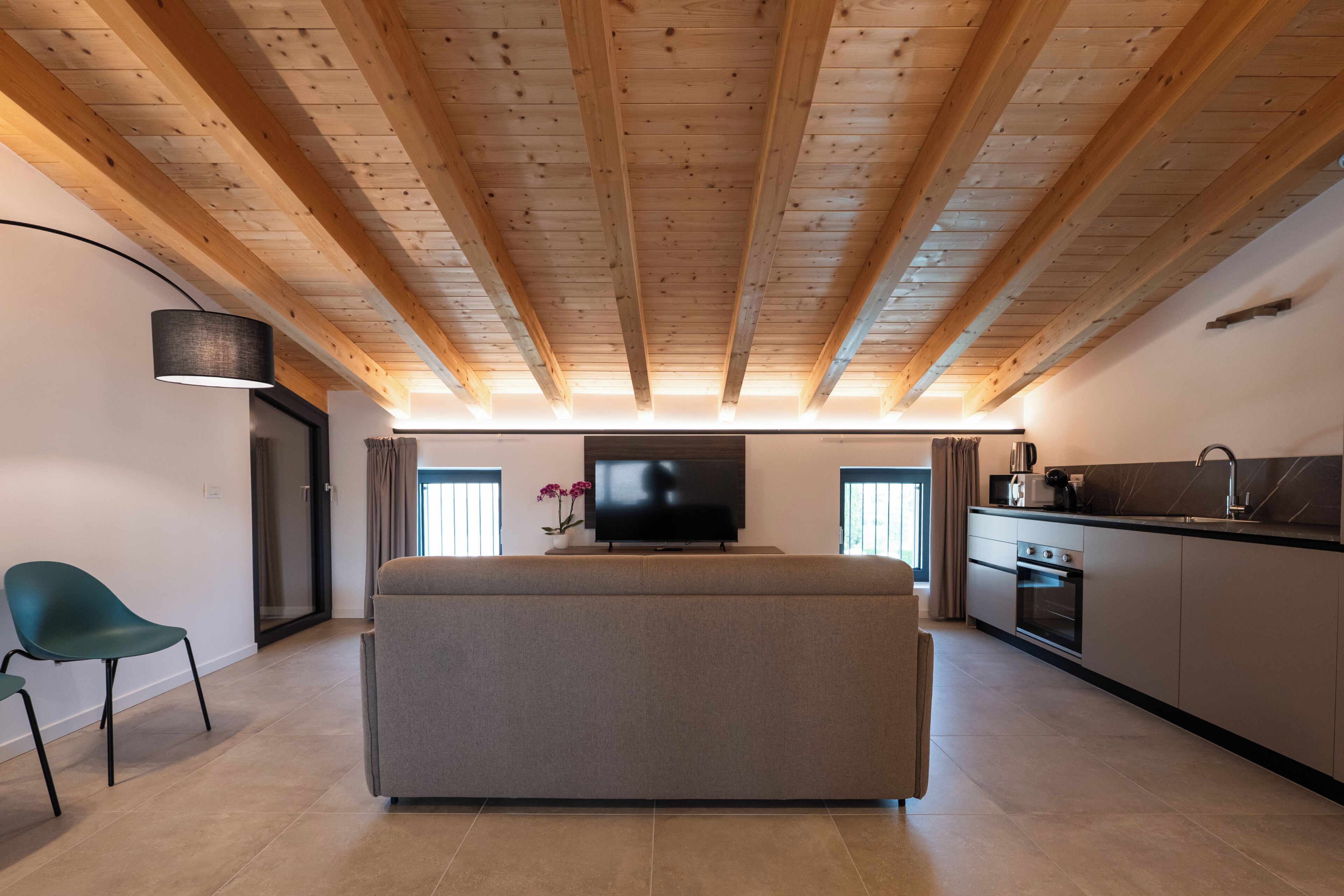A modern living space with a sofa, a television, and a kitchen area.