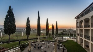 Een binnenplaats met terras, hoge bomen en uitzicht op de zonsondergang.