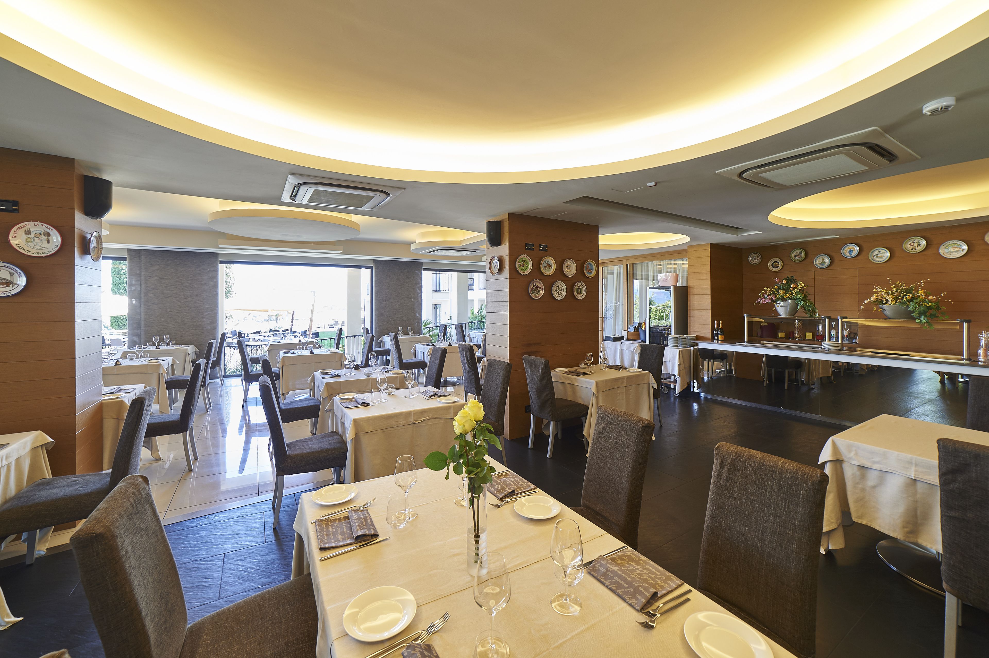 Un restaurante espacioso con varias mesas, sillas y un jarrón decorativo en el centro.