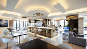 Un moderno vestíbulo de hotel con zona de bar, asientos y un amplio ventanal que proporciona luz natural.