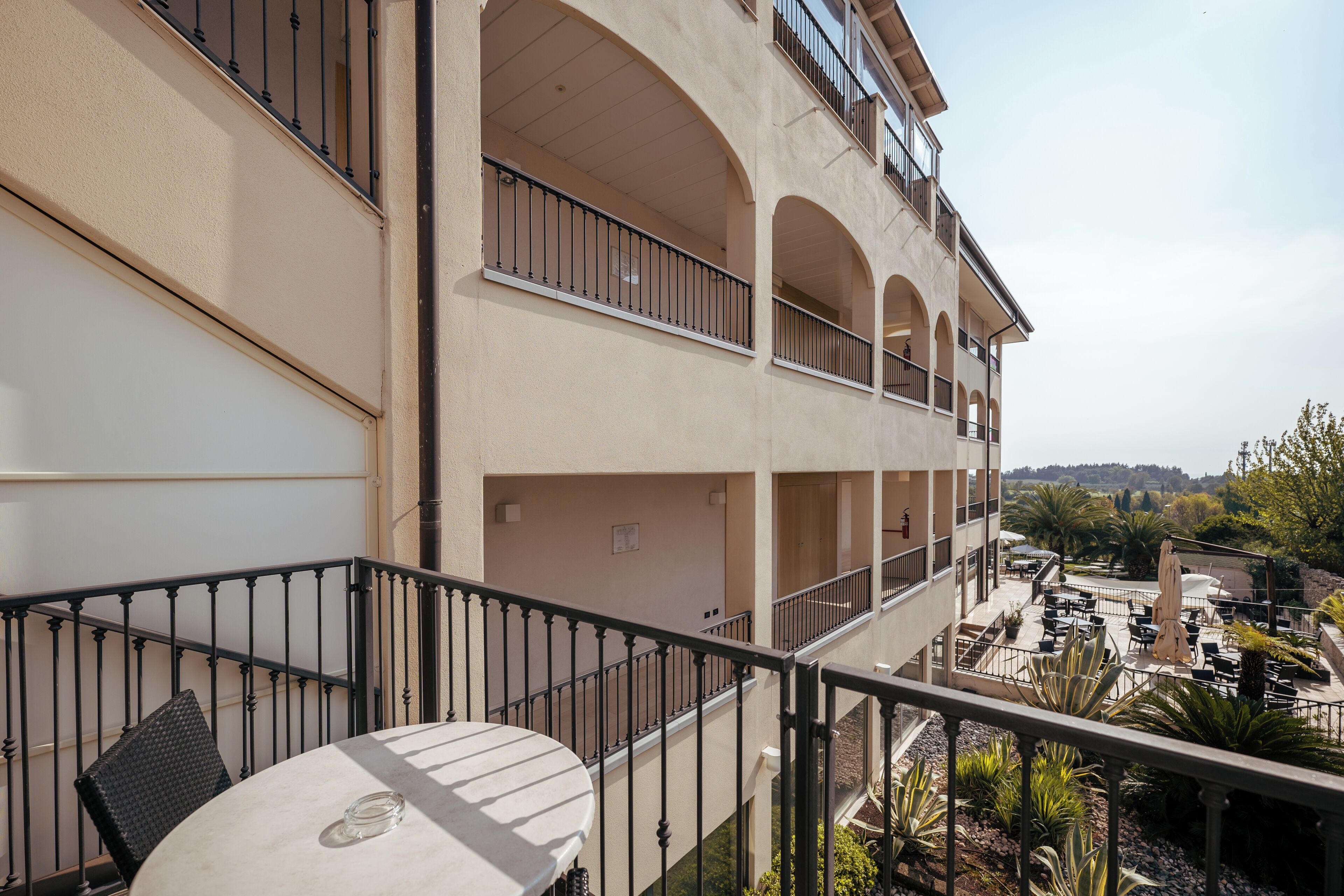 Un edificio de varios pisos con balcones, mobiliario exterior y vistas del paisaje circundante.