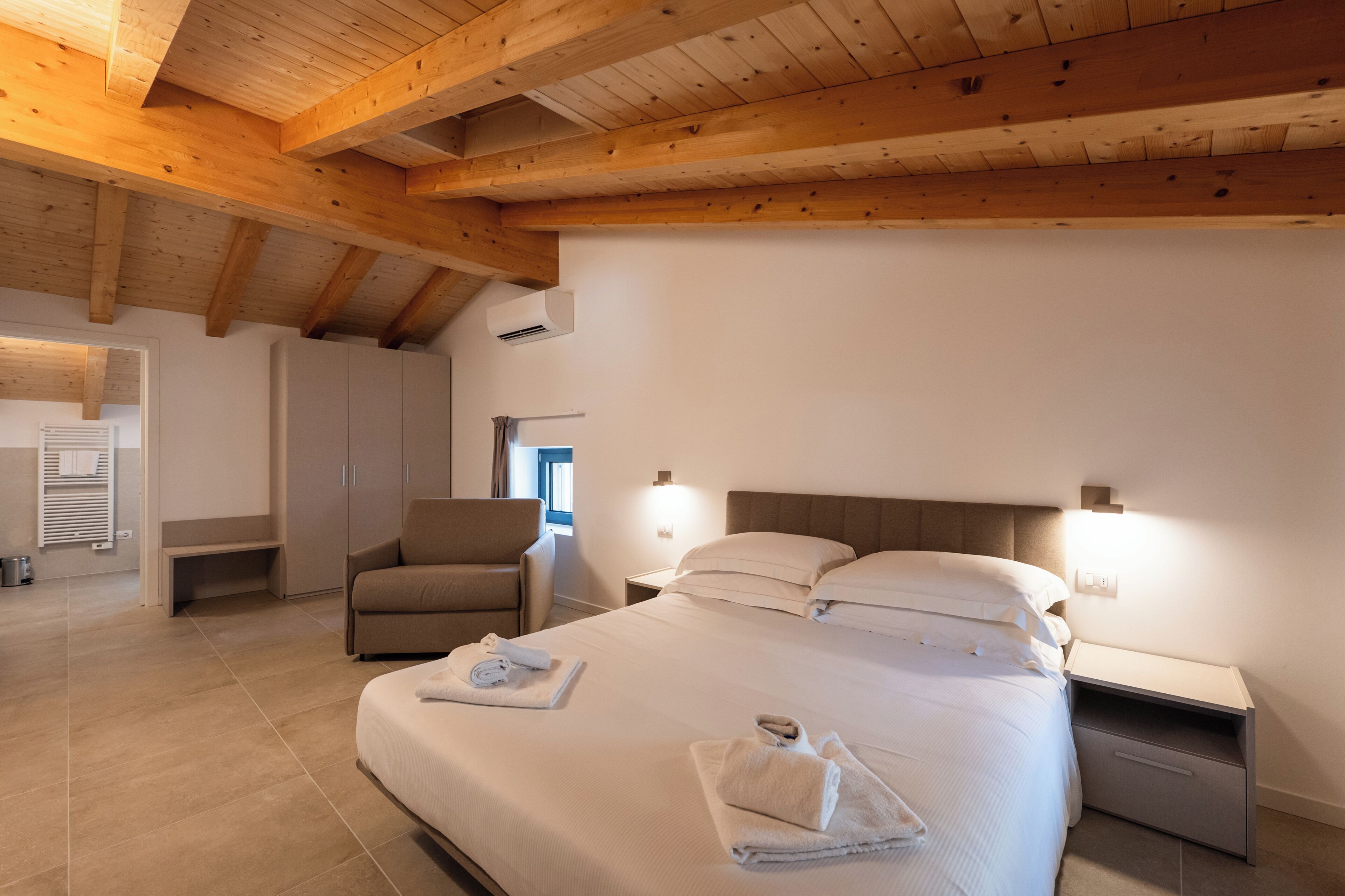 Une chambre à coucher comprenant un lit, des tables de chevet, une chaise et une armoire.