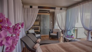 Een balkon met een bed, twee stoelen en een tafel.
