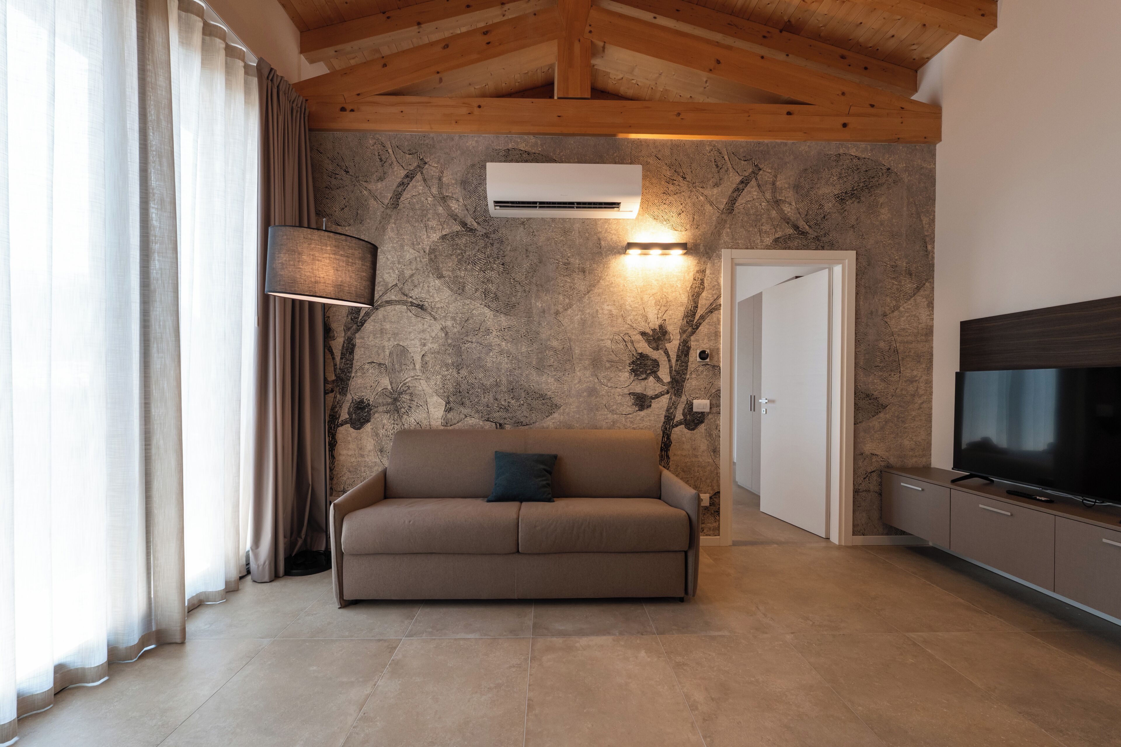 Una sala de estar con un sofá, un televisor y una pared con un diseño texturizado.