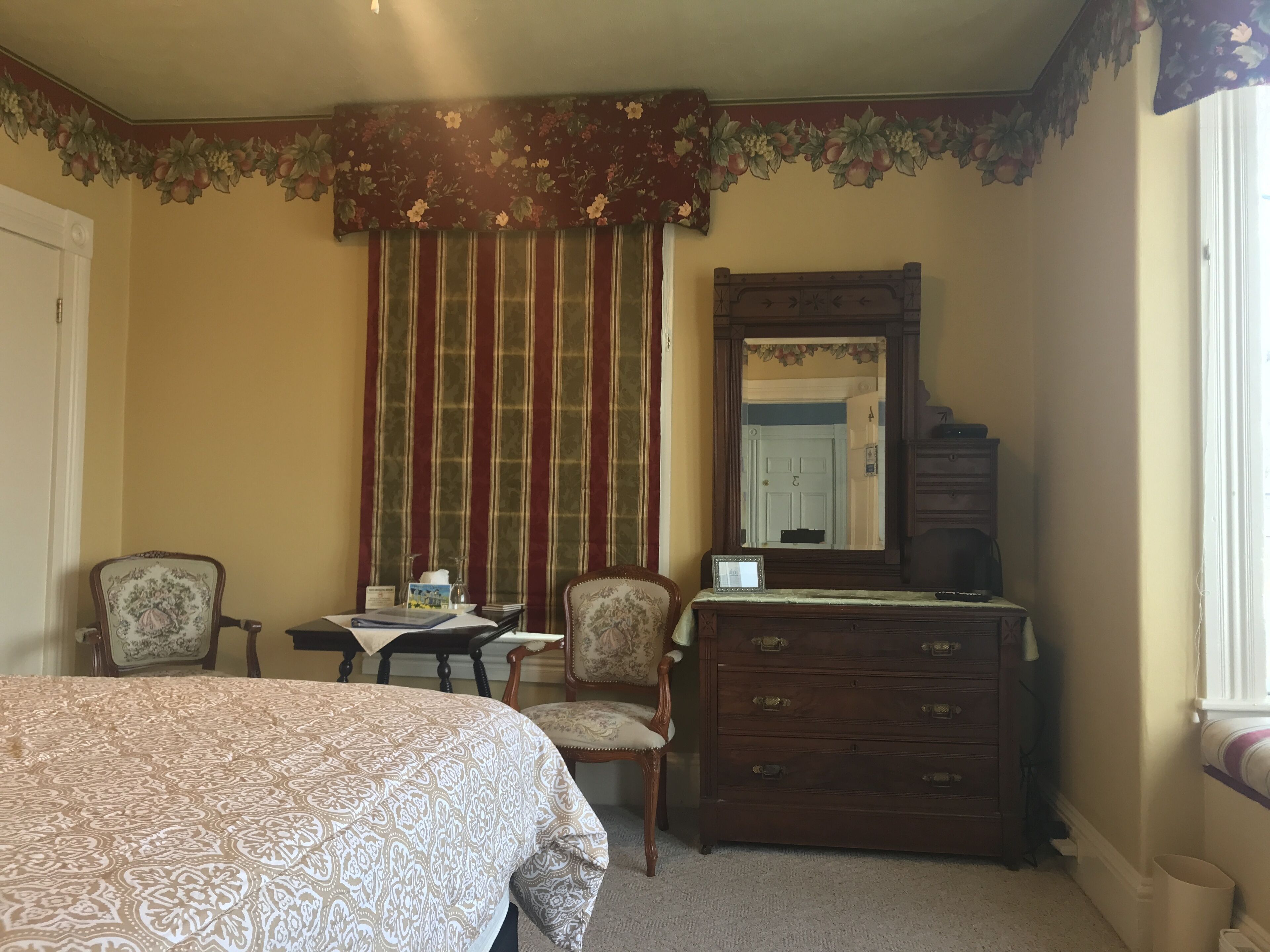 A bedroom with a bed, a dresser, a chair, a desk, and a mirror.