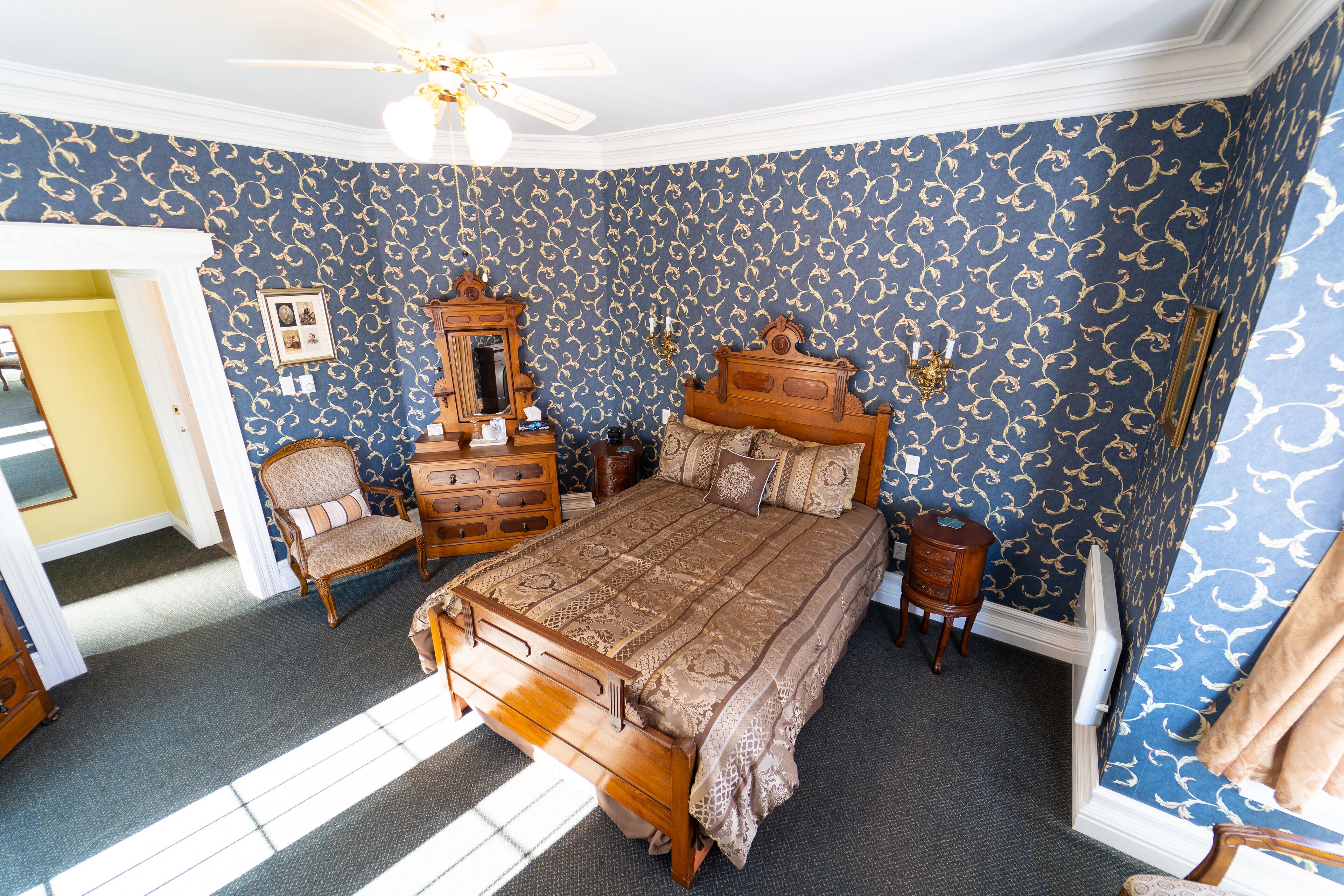 Ein Schlafzimmer mit einem großen Bett, Holzmöbeln und Wandtapete mit Muster.