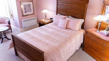 A bedroom with a wooden bed, a nightstand with a lamp, a dresser, and a chair.